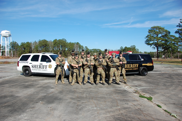 Special Weapons and tactical Deputies group standing in front of Sheriffs SUV’s