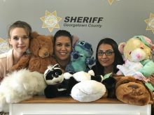 Three plain clothed deputies surrounded by fluffy animal dolls